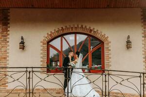 portrait of the bride and groom against the background of the window of an old authentic house, hugs and kisses. Free space. Wedding walk in the park photo