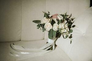 Boda ramo de flores de blanco rosas y verde hojas en un blanco sofá foto