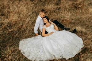 The bride and groom are lying on the dry grass and hugging, a woman in a white wedding dress. Beautiful autumn wedding photo. photo