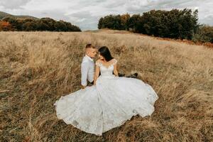 The bride and groom are lying on the dry grass and hugging, a woman in a white wedding dress. Beautiful autumn wedding photo. photo