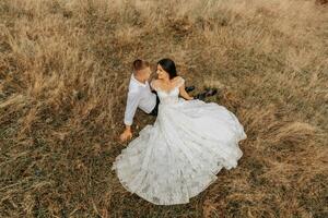 The bride and groom are lying on the dry grass and hugging, a woman in a white wedding dress. Beautiful autumn wedding photo. photo