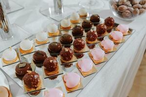 Festive dessert table with sweets. Wedding candy bar, various cakes, chocolates on stands. photo