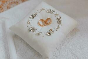 gold wedding rings on a cushion decorated in a circle with silver jewelry stones, preparation for the painting ceremony photo