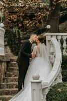 Romantic kiss of the bride and groom after the ceremony on the steps in the garden photo