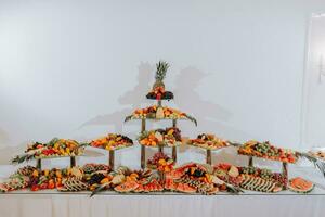 table with various fruit decorations. Watermelon carving, pineapple slices, grapes, orange photo