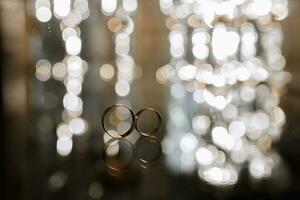 macro shot of wedding rings on a mirror surface with gorgeous bokeh in the background photo