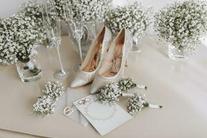 Wedding rings of the bride and groom with wedding bouquets of white flowers. Two beautiful gold wedding rings. Men's and women's rings with ornaments. Women's high-heeled shoes. place for text photo