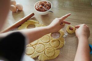 Cocinando hecho en casa galletas con manzana mermelada en un de madera cocina tablero foto