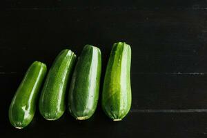 four green fresh zucchini on a black background. Concept of healthy eating photo