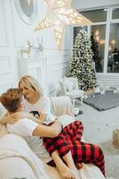 Cheerful and happy couple in matching pajamas lying on sofa. A loving family. The concept of New Year's holidays photo