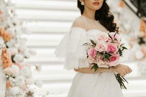 wedding bouquet of roses and greenery in the hands of a girl in a wedding dress photo