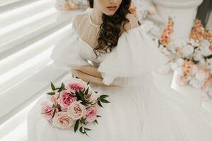 wedding bouquet of roses and greenery in the hands of a girl in a wedding dress photo