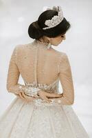 Portrait of beautiful bride in white wedding dress with modern hairstyle and veil, back view. Wedding concept photo