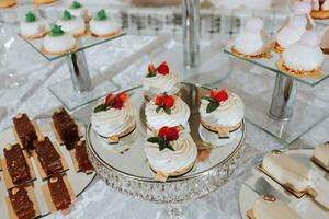 Festive dessert table with sweets. Wedding candy bar, various cakes, chocolates on stands. photo