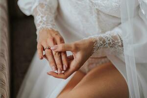 Details Wedding accessories. The bride holds a gold wedding ring with a diamond in her hands, cropped photo. Beautiful hands. Open legs photo