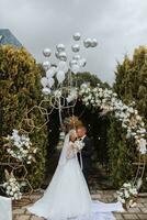 A young wedding couple at a wedding painting ceremony. The bride and groom kiss against the background of balloons flying into the sky photo