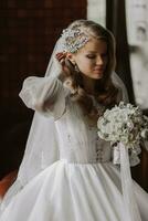 portrait of a blonde bride in a wedding dress with sleeves and a bouquet of flowers in her hands photo