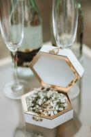 Gold wedding rings on a white box decorated with gypsophila flowers photo