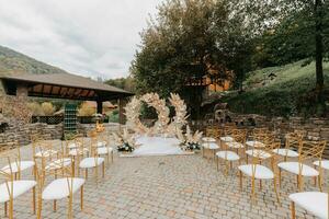 Boda ceremonias en el parque para el novia y novio. el arco es hecho de Fresco flores y seco cañas lejos Boda ceremonias sillas con oro color foto