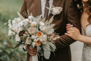 Close-up of a wedding bouquet in the hands of the bride and groom in nature photo