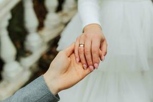 Hands of the bride and groom close-up. The groom holds the bride's hand photo