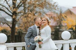 The groom tenderly kisses his bride on the cheek in a luxurious garden photo