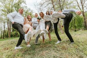 Boda caminar en el bosque. novias y su amigos actitud en contra el antecedentes de el bosque. un grande grupo de personas son teniendo divertido a su amigos' Boda foto