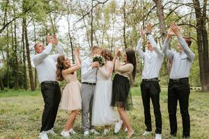 Boda caminar en el bosque. novias y su amigos actitud en contra el antecedentes de el bosque. un grande grupo de personas son teniendo divertido a su amigos' Boda foto