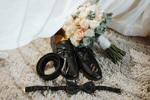 details of the groom. men's belt, wedding rings, men's bow tie, wedding bouquet, men's shoes photo