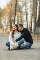 un hombre cerca su embarazada esposa, descansando en un otoño parque. apoyo de el marido durante el embarazo. el tema de mental salud durante el embarazo foto