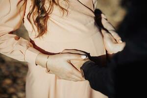 A man and his pregnant wife, he touches her pregnant belly, close-up photo. Happy family concept. photo