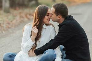 un hombre cerca su embarazada esposa, descansando en un otoño parque. apoyo de el marido durante el embarazo. el tema de mental salud durante el embarazo foto