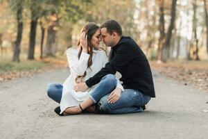 A man near his pregnant wife, resting in an autumn park. Support of the husband during pregnancy. The topic of mental health during pregnancy photo