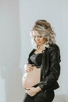 elegante estudio retrato de un hermosa embarazada joven mujer en un negro traje foto