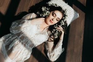 beautiful pregnant woman in a lace transparent dress lying on the floor in flowers. Concept of pregnancy, motherhood, preparation and waiting. The beauty of a woman during pregnancy photo