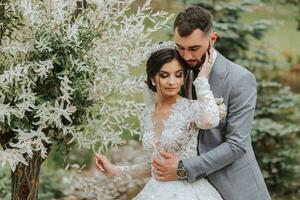 European wedding couple in the park near the stairs. The bride in a beautiful dress with a long train and sleeves. Groom in a classic suit photo