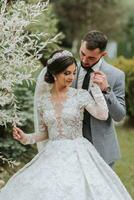 European wedding couple in the park near the stairs. The bride in a beautiful dress with a long train and sleeves. Groom in a classic suit photo