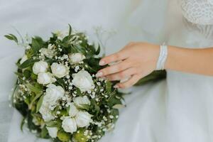 hermosa novia en blanco y un ramo de flores de flores en su manos de cerca foto