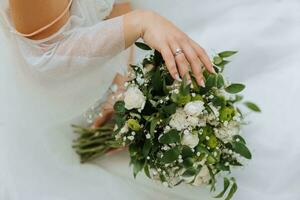 hermosa novia en blanco y un ramo de flores de flores en su manos de cerca foto