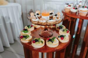 Festive dessert table with sweets. Wedding candy bar, various cakes, chocolates on stands. photo