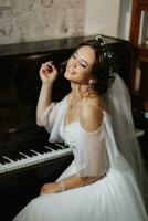 Portrait of a beautiful girl in a wedding dress and a wreath of fresh flowers on her head, playing the piano, playing alone photo