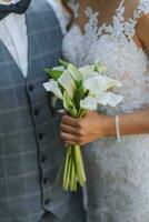 wedding bouquet of calla flowers in the bride's hand close-up, decoration on the girl's hand, white wedding dress photo