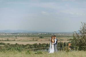 portrait of a stylish groom and bride against the background of summer mountains. the concept of a rustic wedding in the mountains, happy bohemian newlyweds. photo