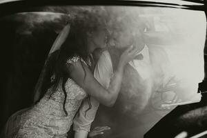 un lujoso y elegante Boda Pareja tiernamente abrazo en el medio de un elegante retro coche. el foto estaba tomado mediante el parabrisas. maravilloso novia y hermoso novio en retro estilo.