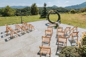 The wedding arch in the park is made of dry reeds on the background of the forest in blurred focus. Away wedding ceremony. Decorated chairs for the ceremony photo