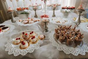 festivo postre mesa con dulces Boda caramelo bar, varios pasteles, chocolates en soportes foto