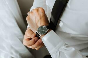 a man in a white shirt puts a watch on his hand, close-up photo