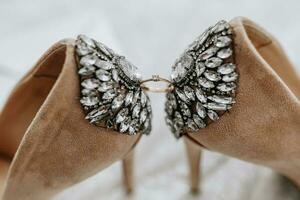 Boda Zapatos de el novia en un alto tacón de beige color con piedras encima el tacón, Entre el Zapatos un oro anillo de el novia foto