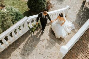 portrait of a young beautiful wedding couple in the garden, the bride in an off-the-shoulder wedding dress circling and showing off her dress, the groom in a black classic suit photo