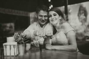 Side view portrait of a loving European couple laughing while enjoying a date in a cafe. Black and white photo